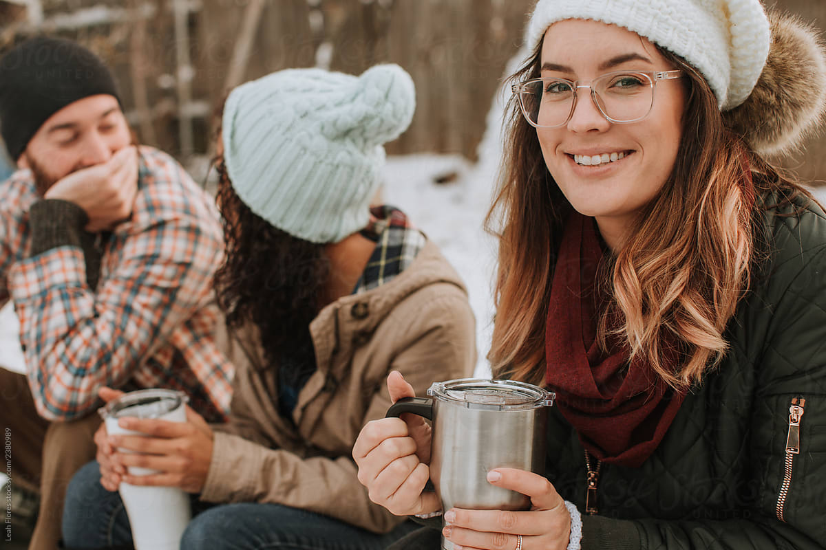 Group of Friends Sitting with Coffee at Winter Campsite