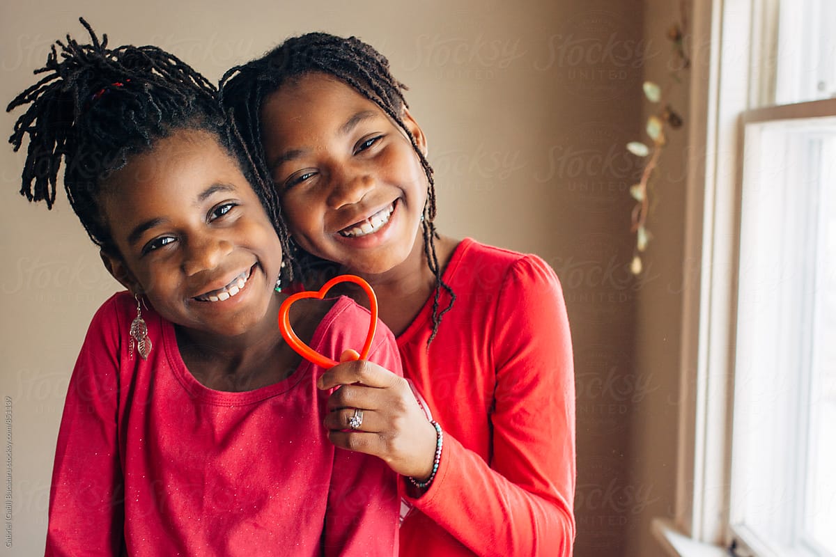 Cute African American girls in red holding a heart shaped cookie cutter