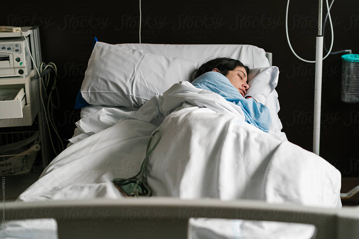 Pregnant woman sleeping in hospital bed under blanket