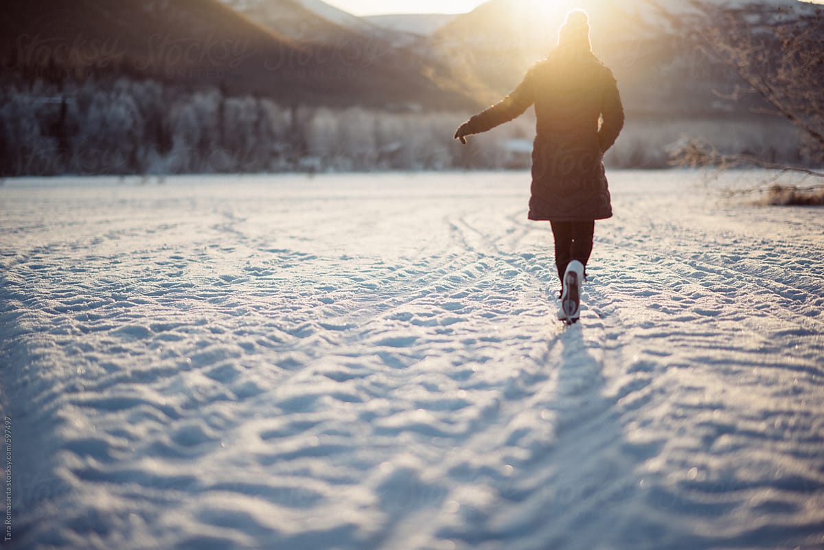 Young woman in ice skates on a snow covered frozen lake in Alaska