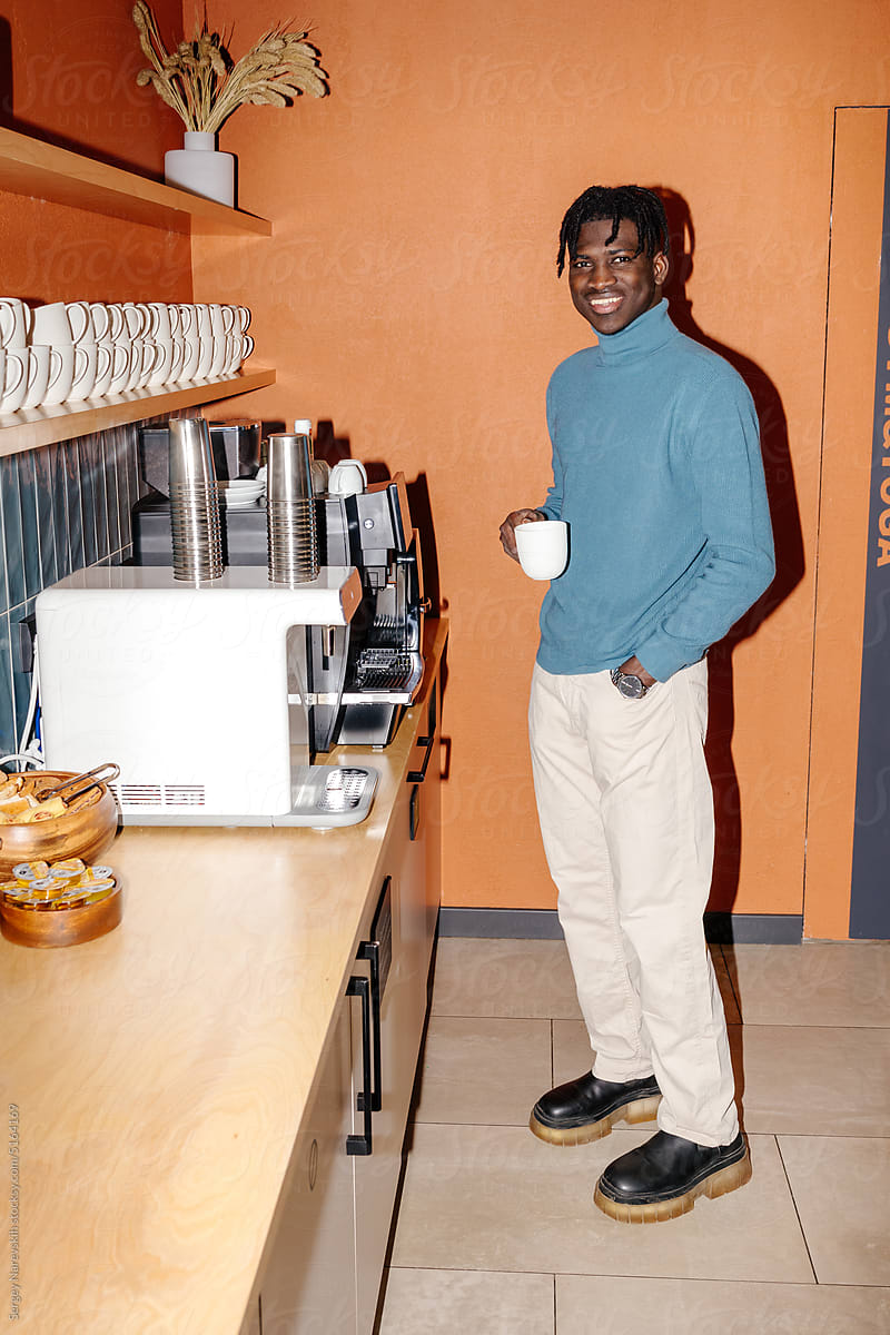 Happy man with cup of coffee in workplace