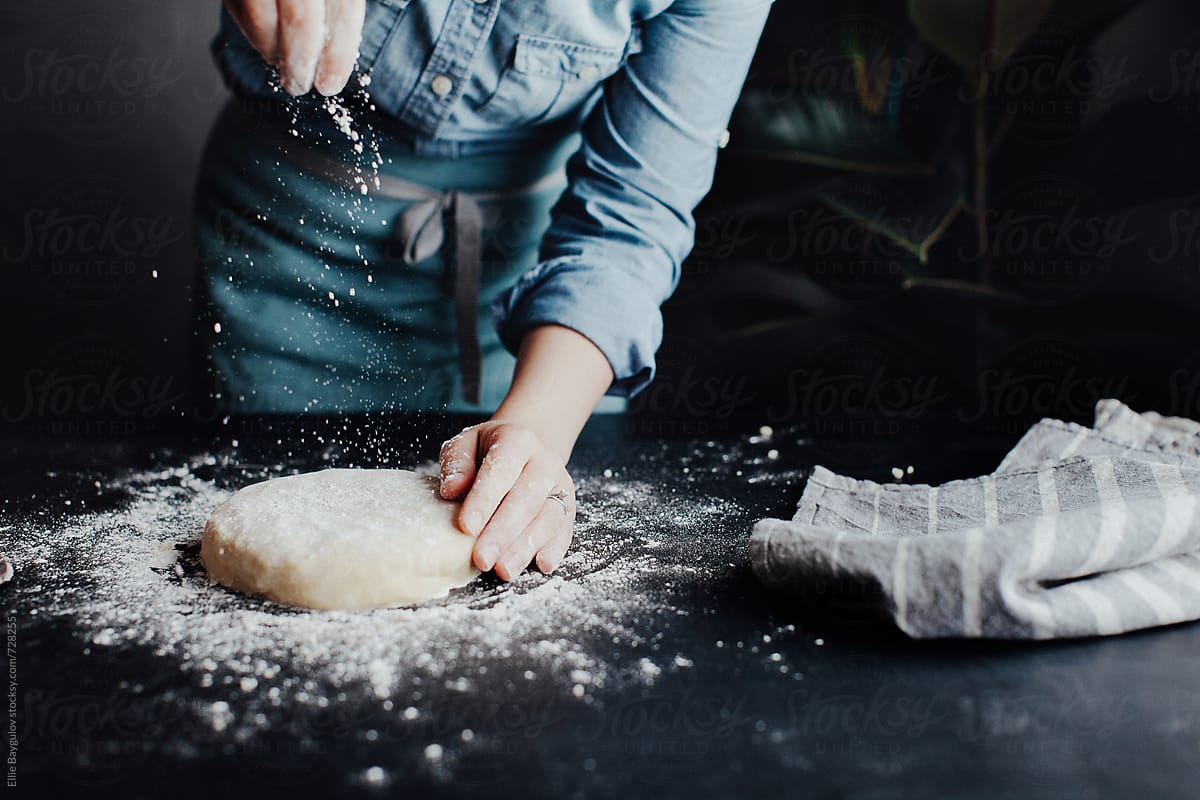 Woman Sprinkling Flour Over Dough By Stocksy Contributor Ellie Baygulov Stocksy