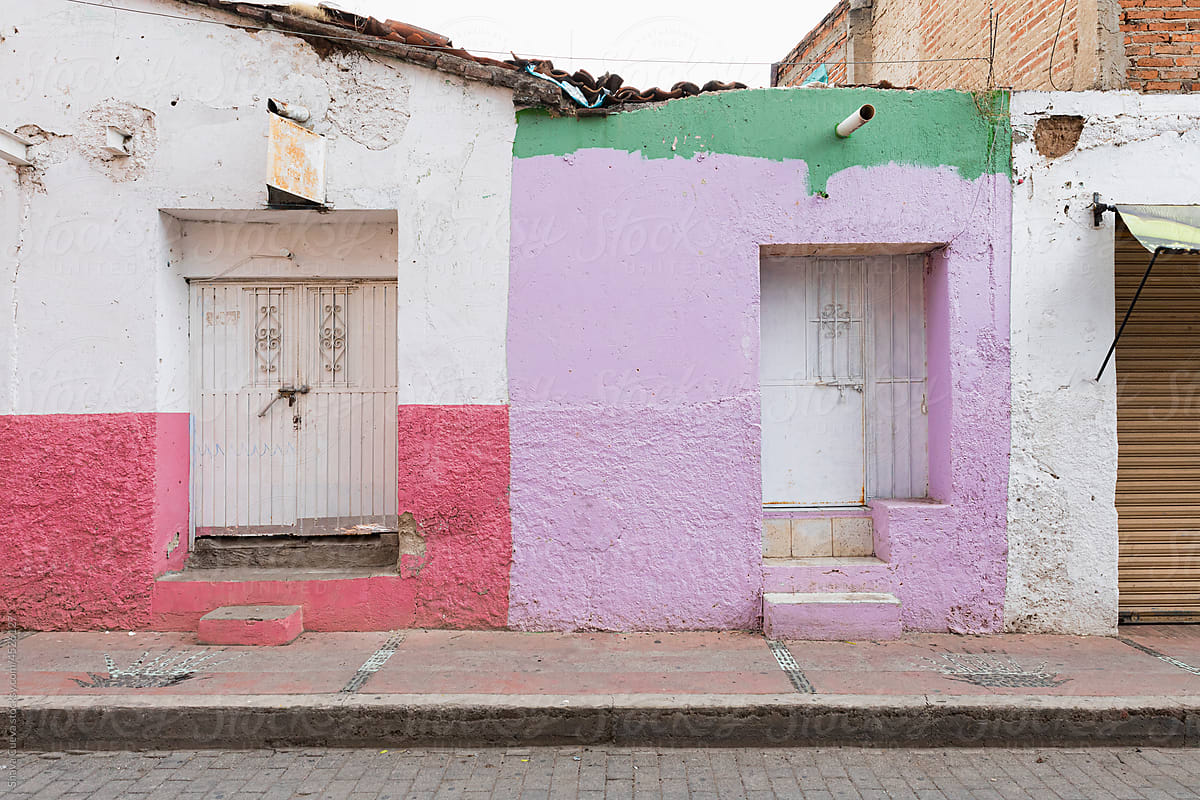 Two businesses painted with colorful walls closed with white doors