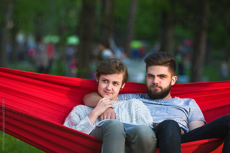 Young couple sitting in a red hammock in the park