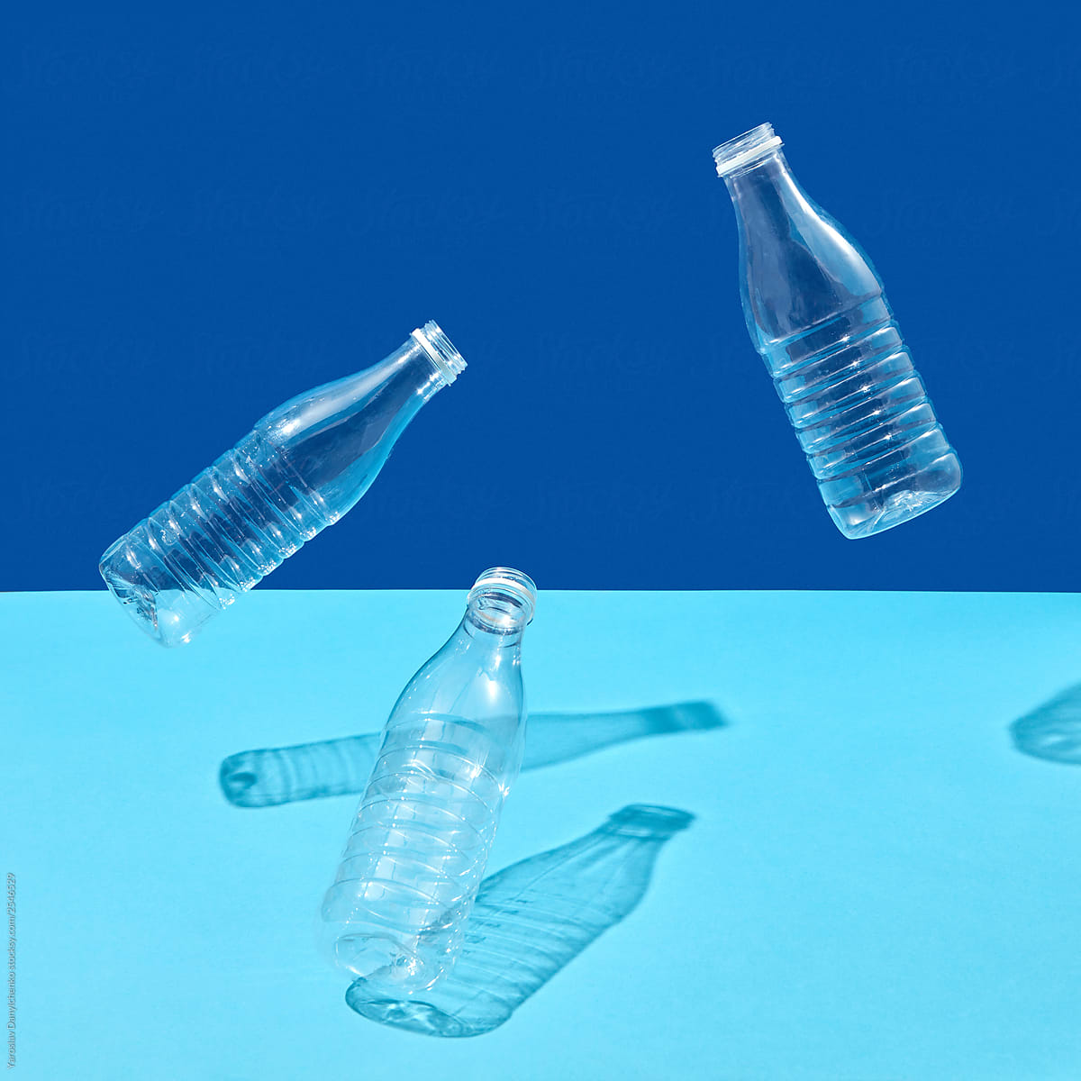 Empty plastic bottles in the air on a duotone blue background