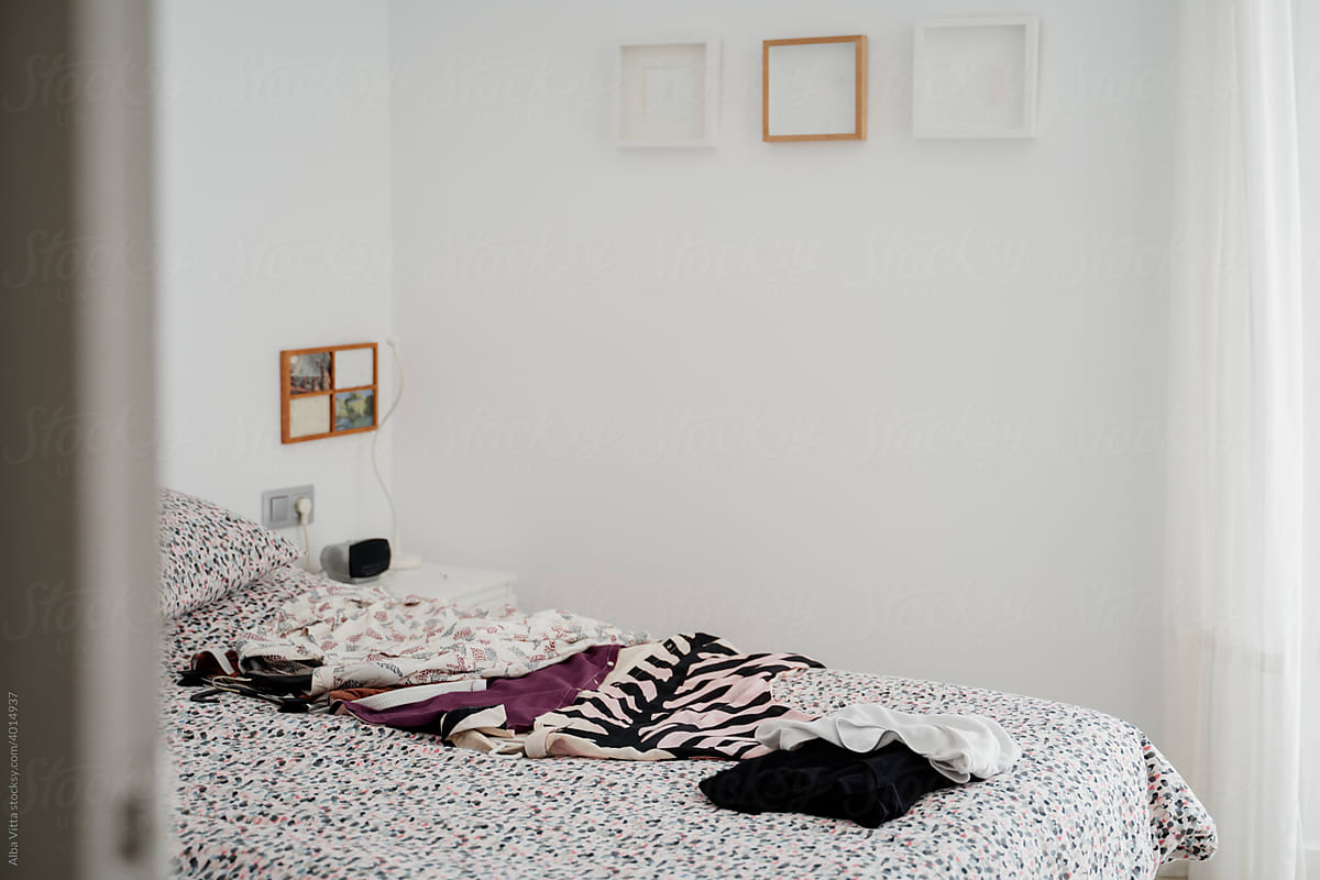 Clothes on top of bed in bright bedroom during daytime