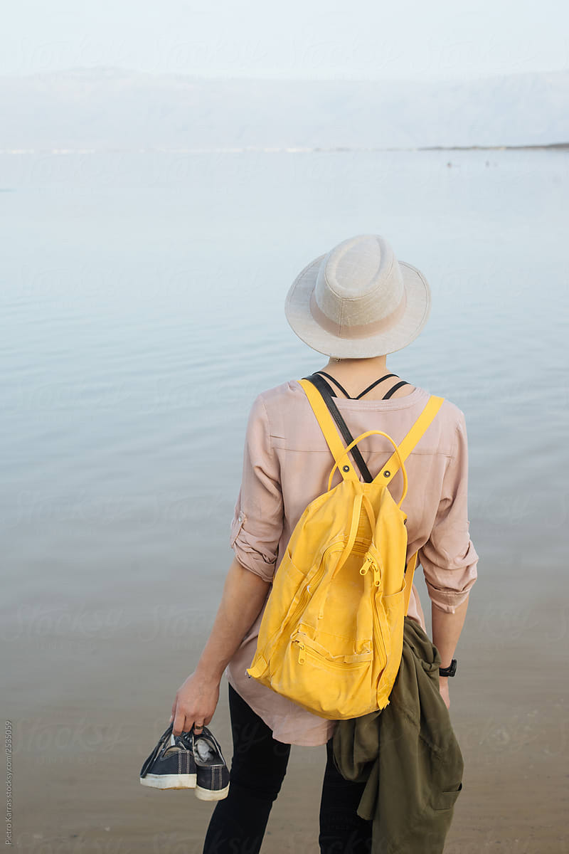 Female traveler with backpack looking at water