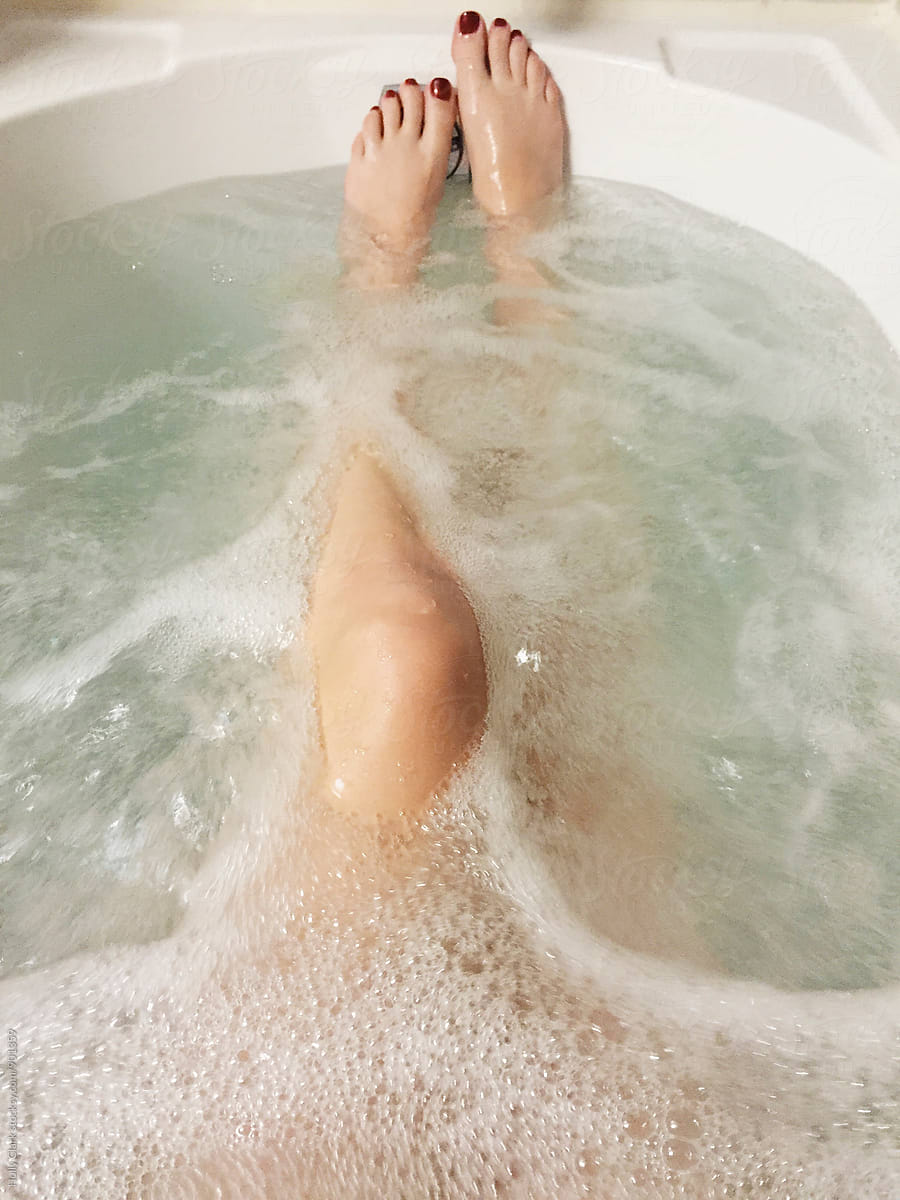 Woman's naked legs in bathtub full of bubbly water