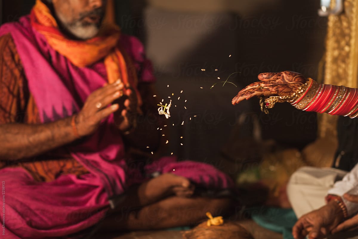 Bride\'s hand throwing flower petals in a fire during hindu wedding ceremony