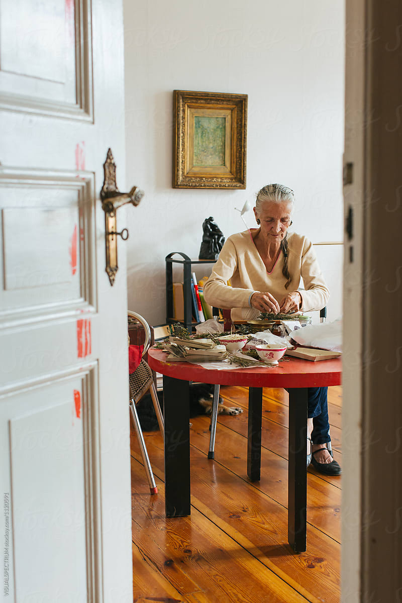 Indoor Portrait of Elderly Female Herbalist Tying Natural Smudge Stick
