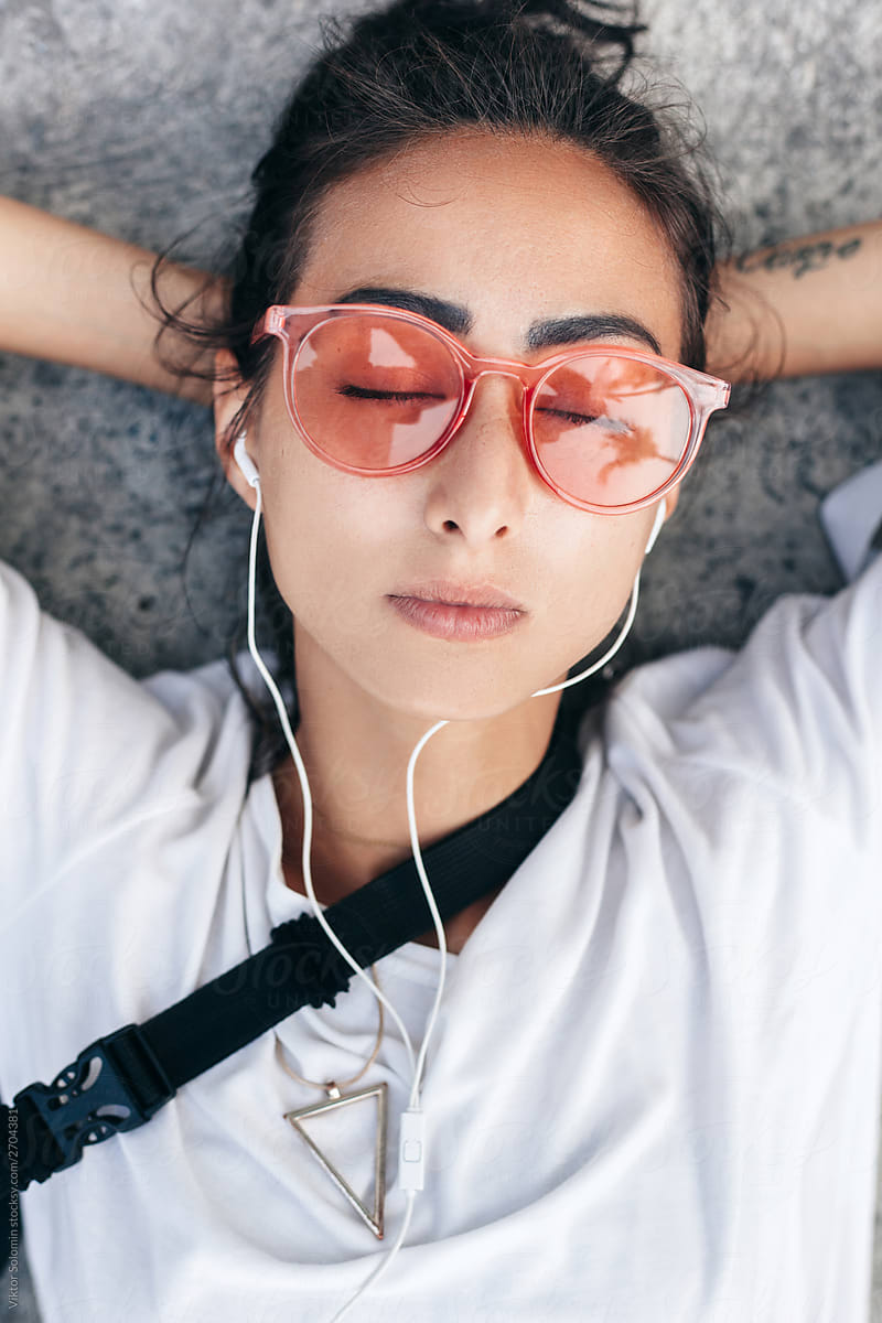 Closeup portrait of young brunette with calm face, closed eyes and pink transparent sunglasses