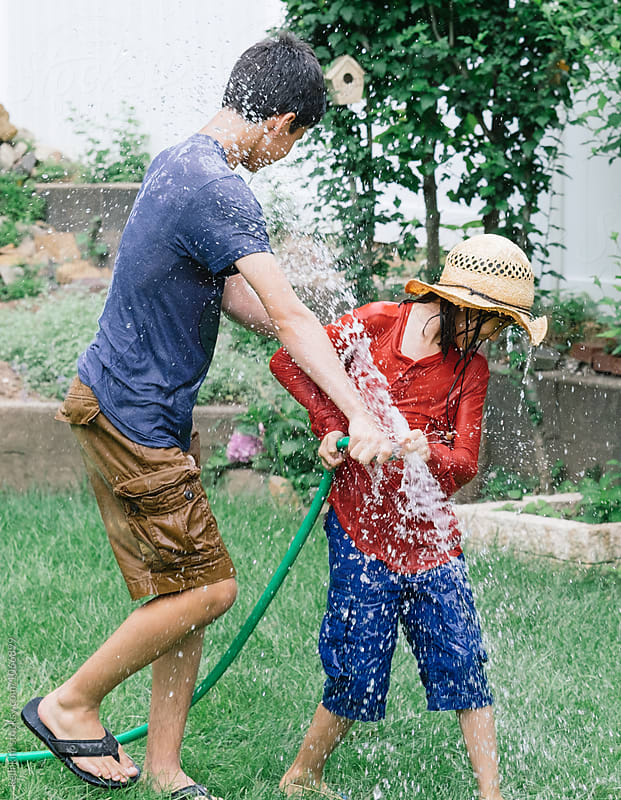 Brothers having water fight with hose