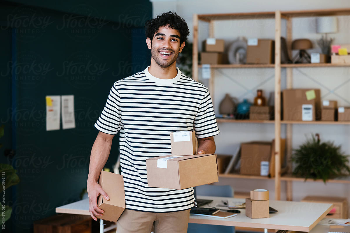 Cheerful Hispanic man with parcels working in delivery office