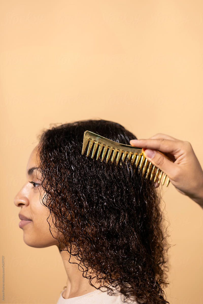 A woman combs her wet curly hair with a comb.