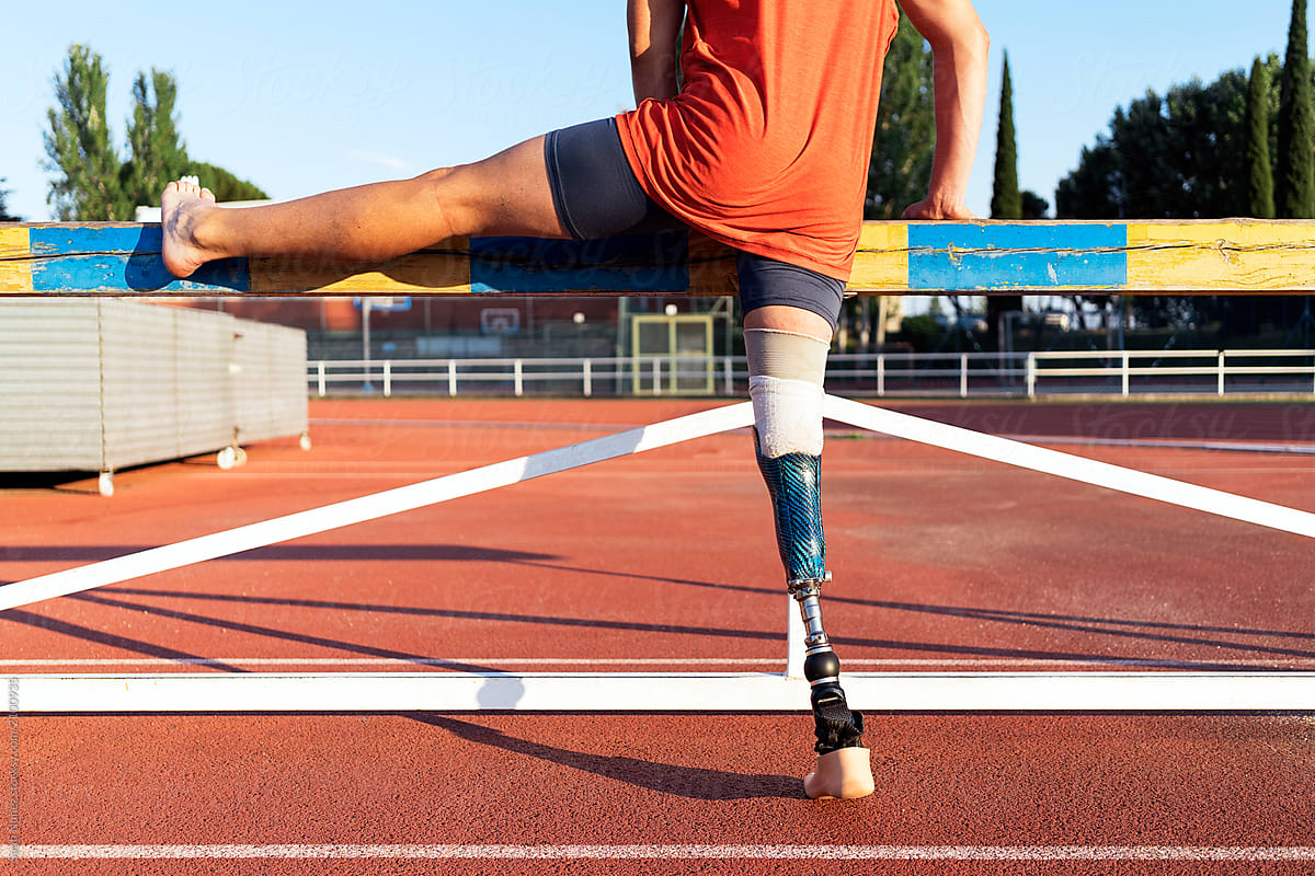 Unrecognizable disabled man athlete stretching with leg prosthesis