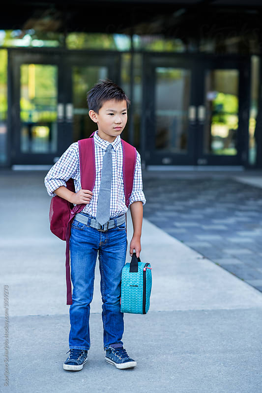 Back to school: Asian kid carrying a lunch bag in school