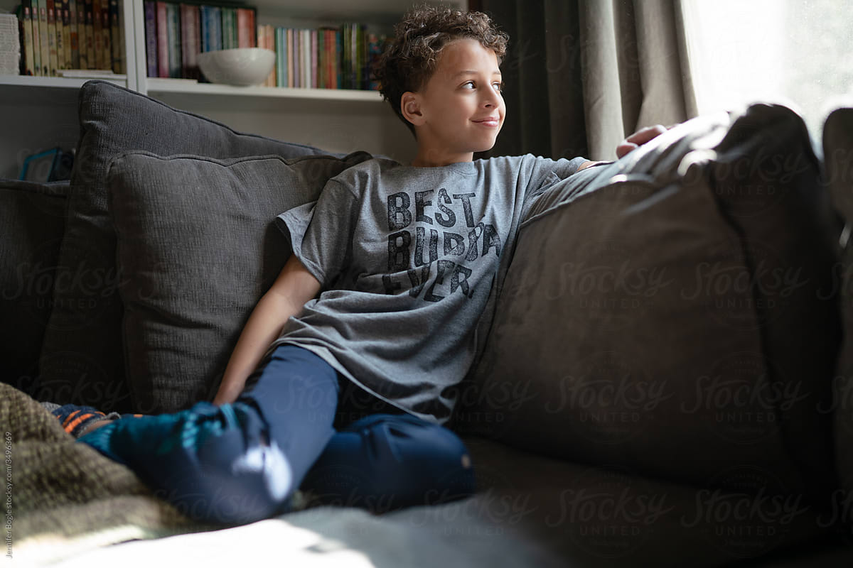 Boy looks out window in living room