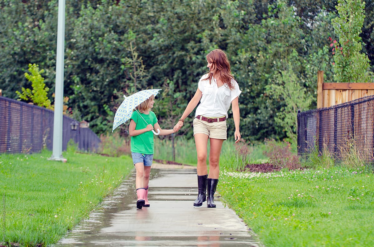 mother and daughter walking with umbrella