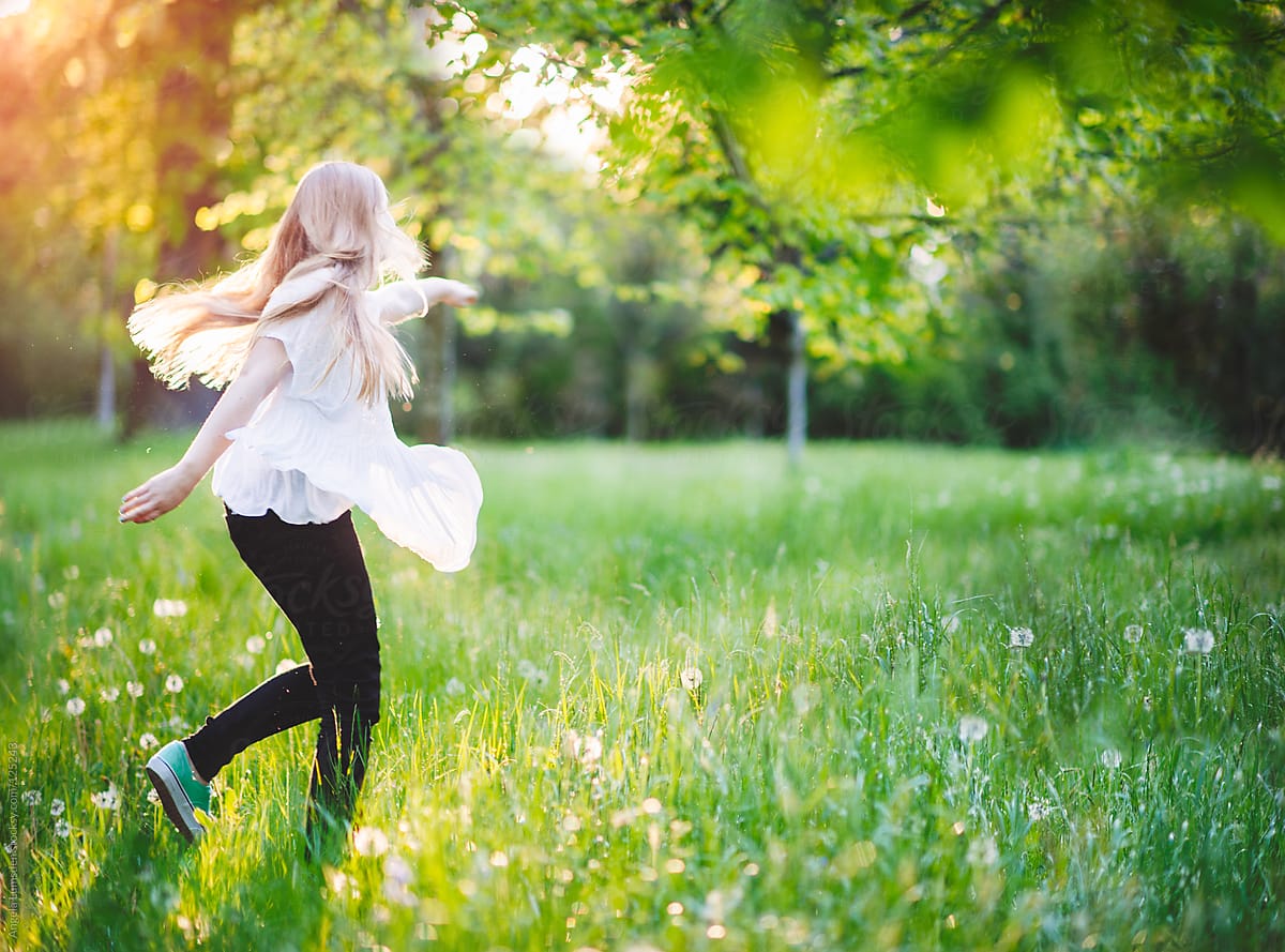 Girl Running Through A Field Of Dandelions In Evening Sun By Angela Lumsden