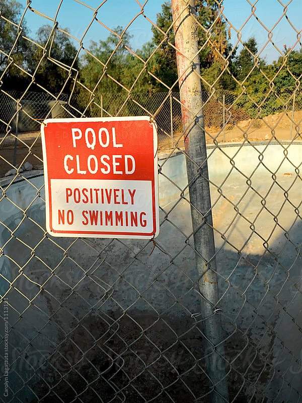 Sign saying Pool is Closed - Positively no swimming next to an empty pool