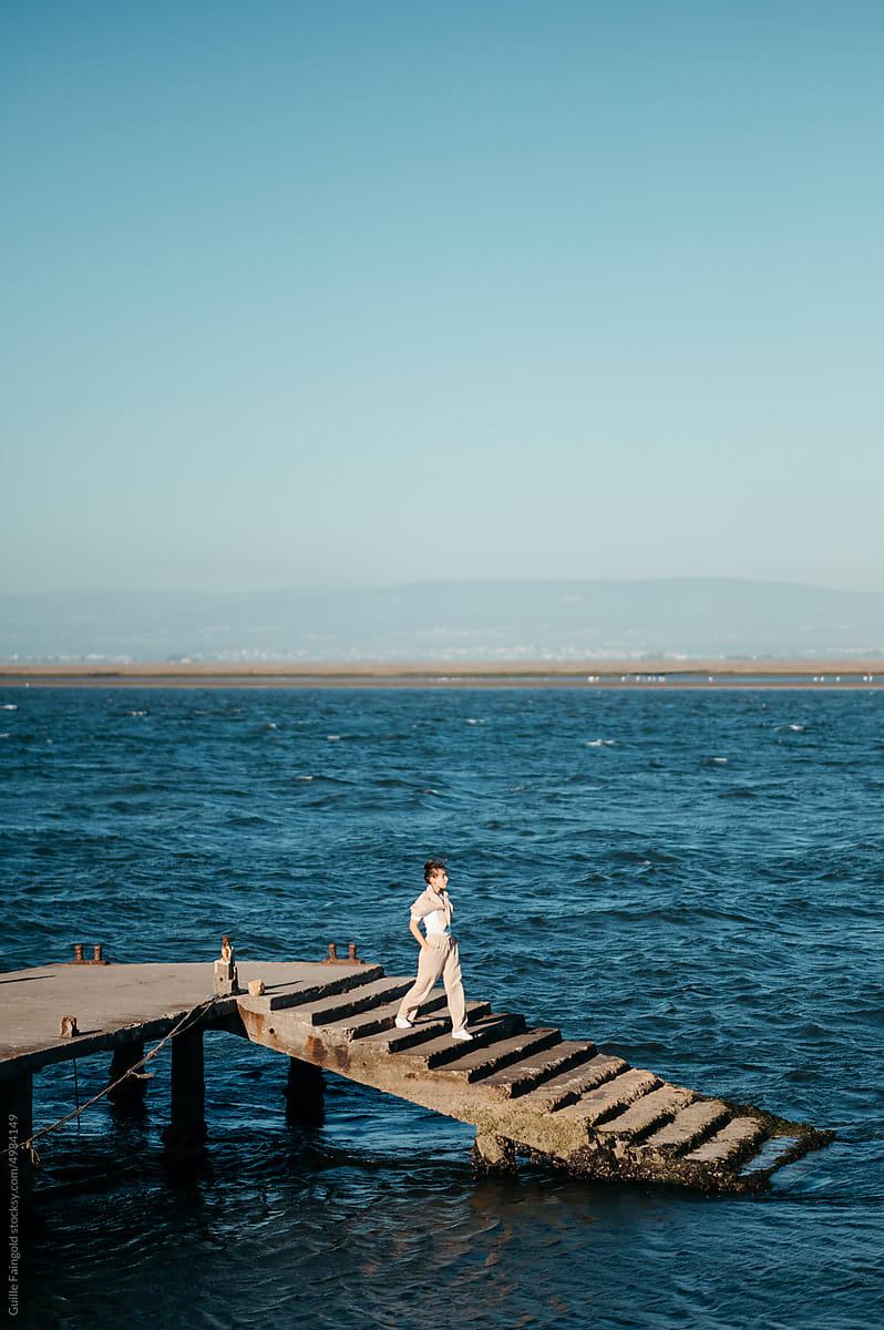 Woman walks down pier.