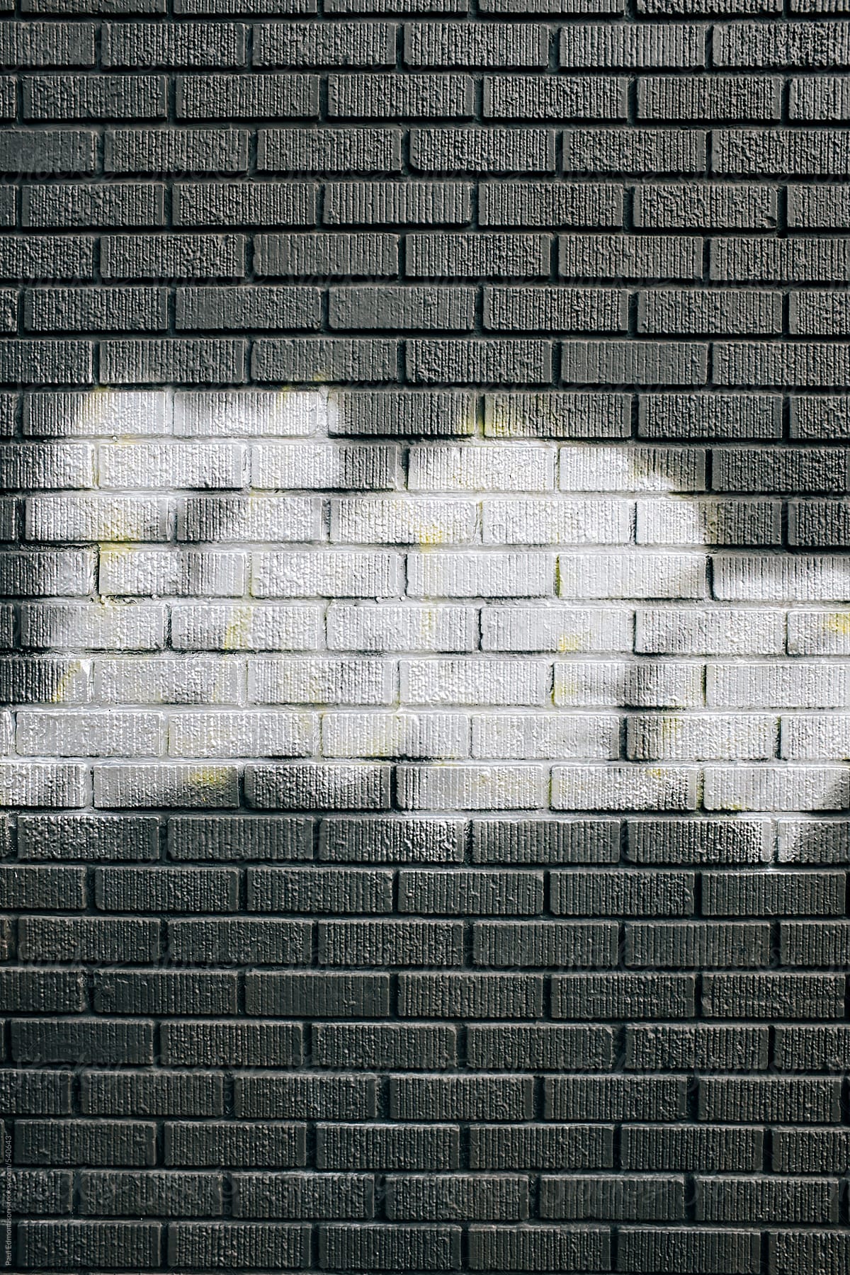 Metallic silver spray paint covering graffiti tags on brick wall