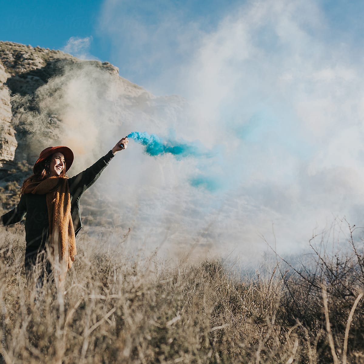 Cheerful teenager playing with color smoke bombs in the countryside
