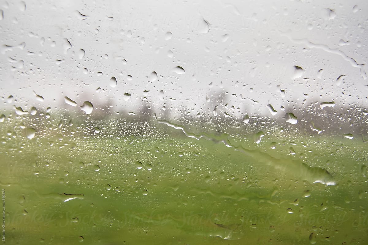 Train window covered with raindrops, stormy landscape