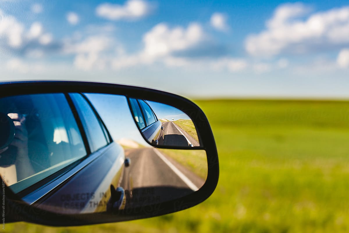 An RV in the side mirror, shot from inside a car on a road trip