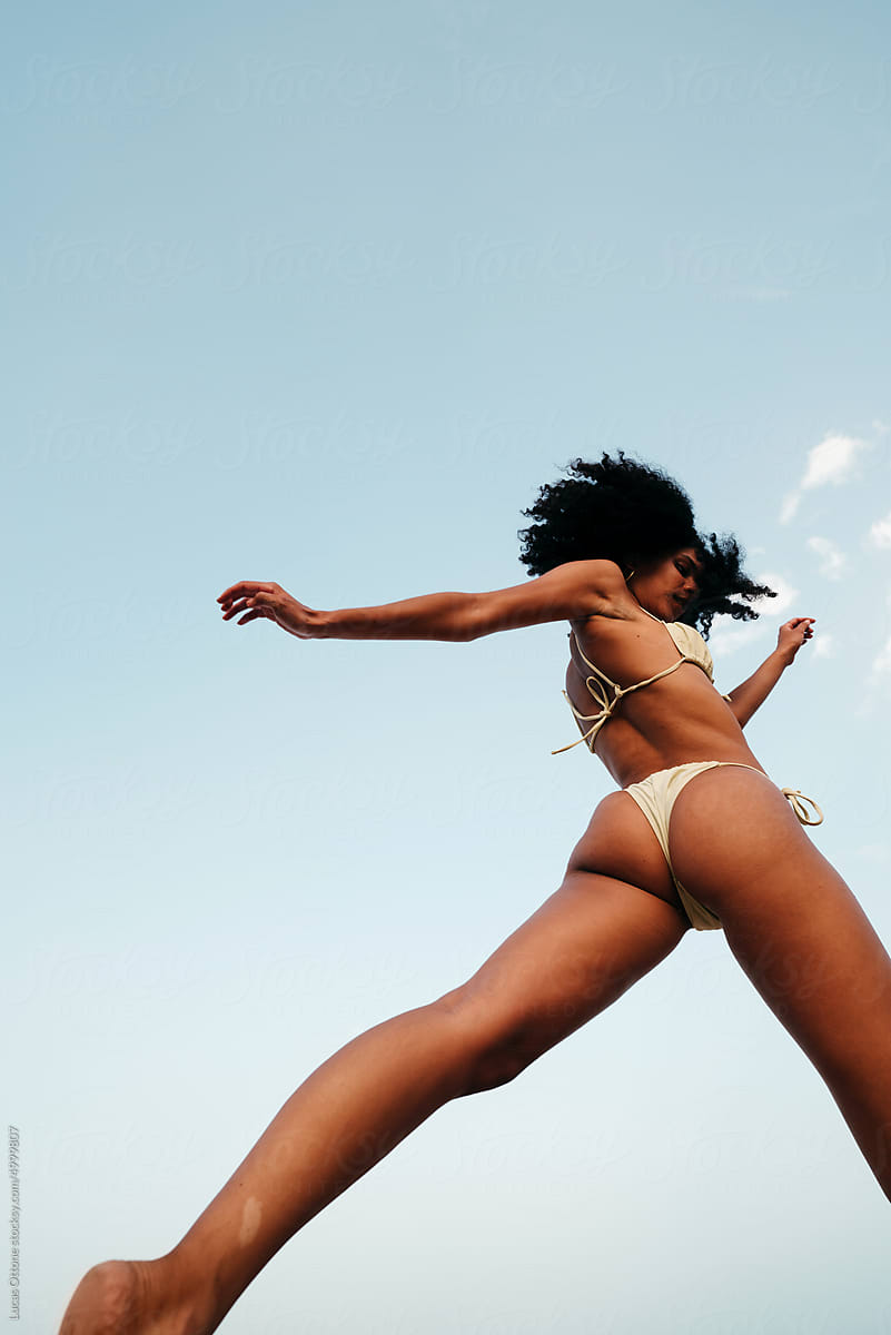 Woman with long legs jumping in a bikini
