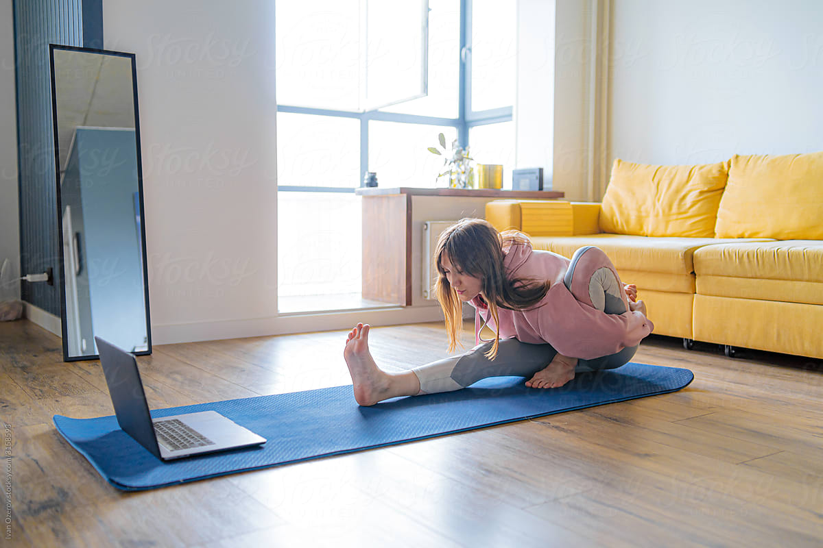 young woman doing yoga at home via video calling