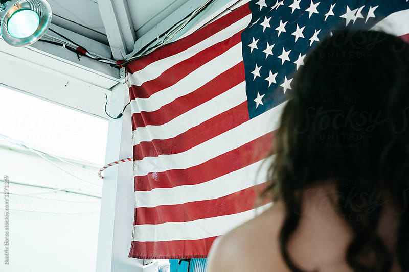Teenager girl from behind in front of an American flag on a wall