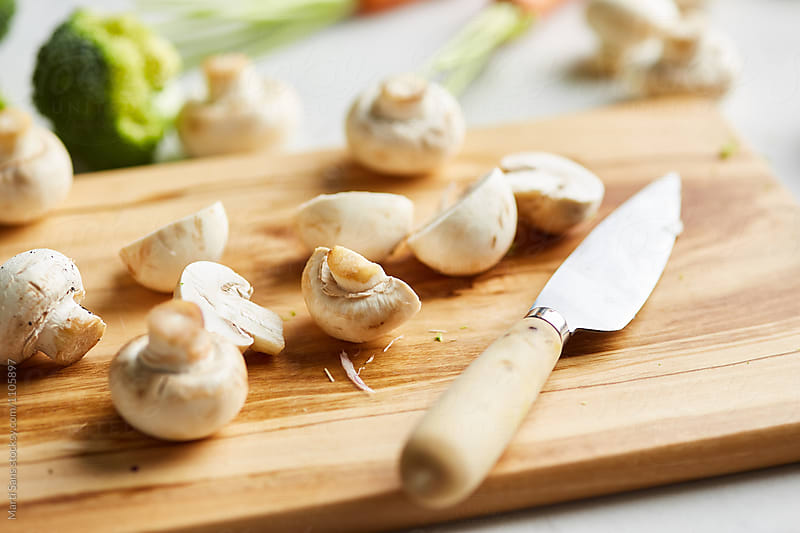 Cut mushrooms on board with knife