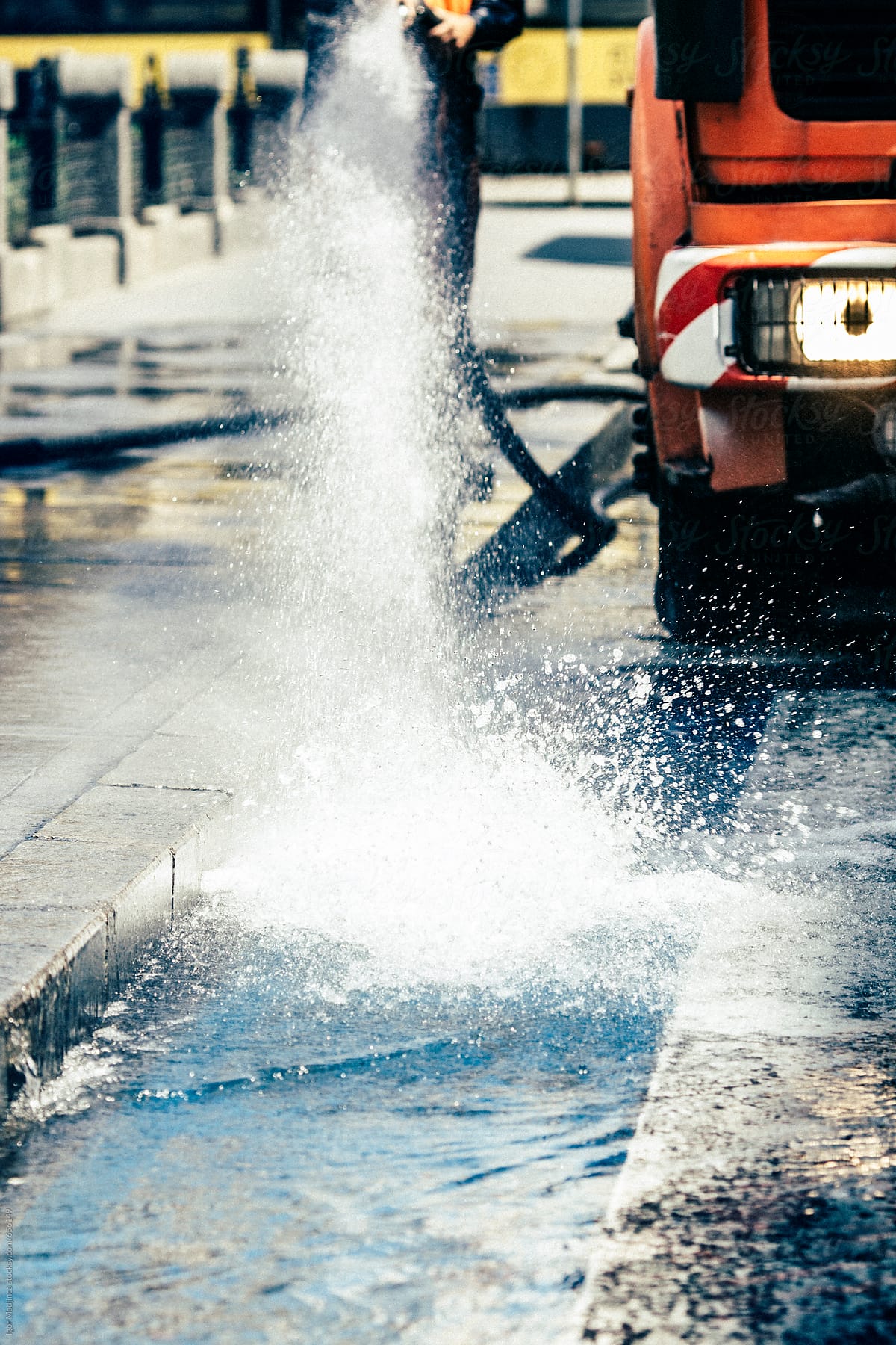 water, street cleaner, worker using a  hose to clean off the dirt