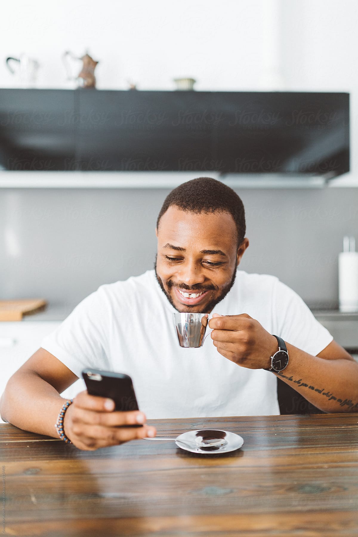 Smiling man drinks coffee and checks phone