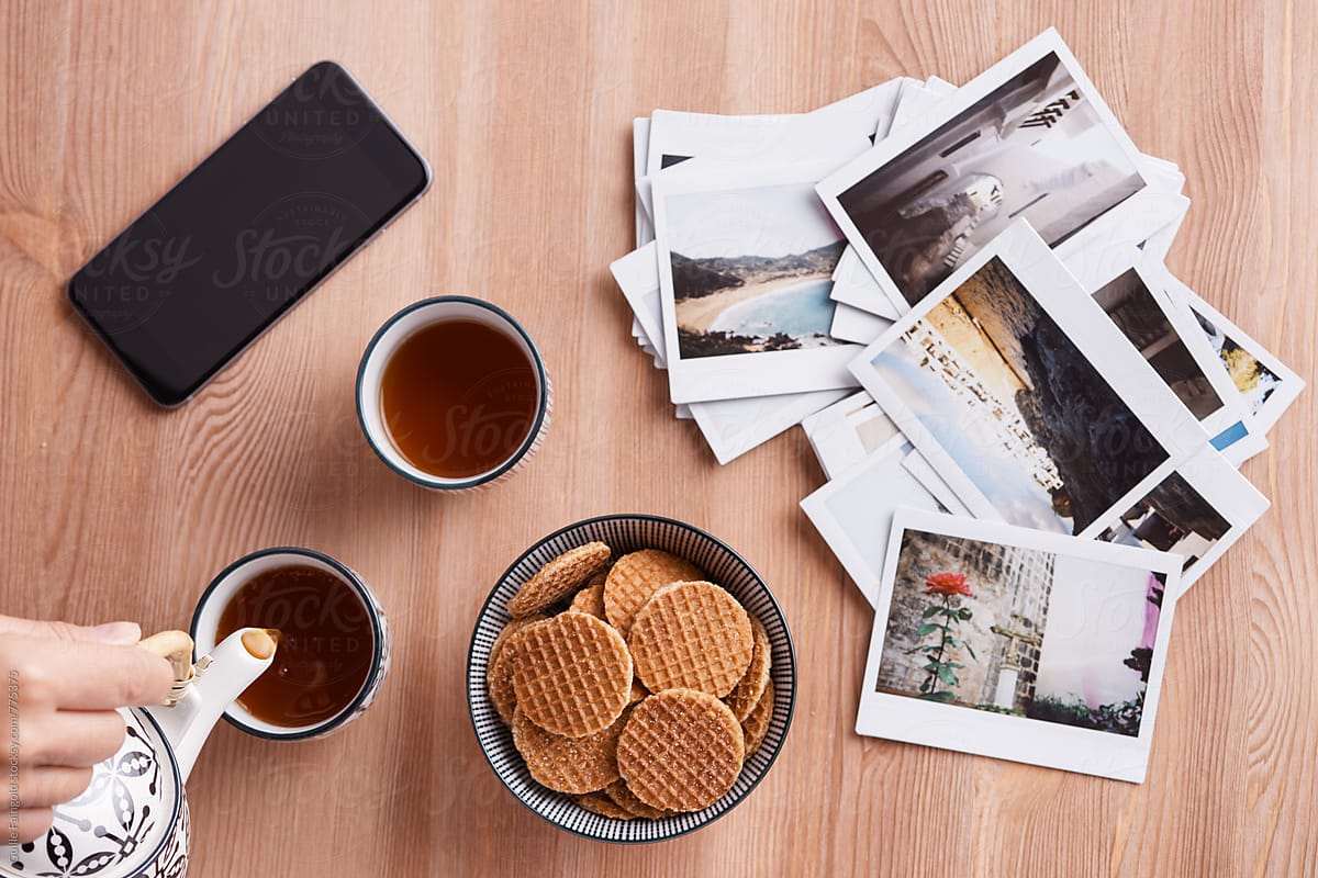 Crop person during tea time with biscuits and photos
