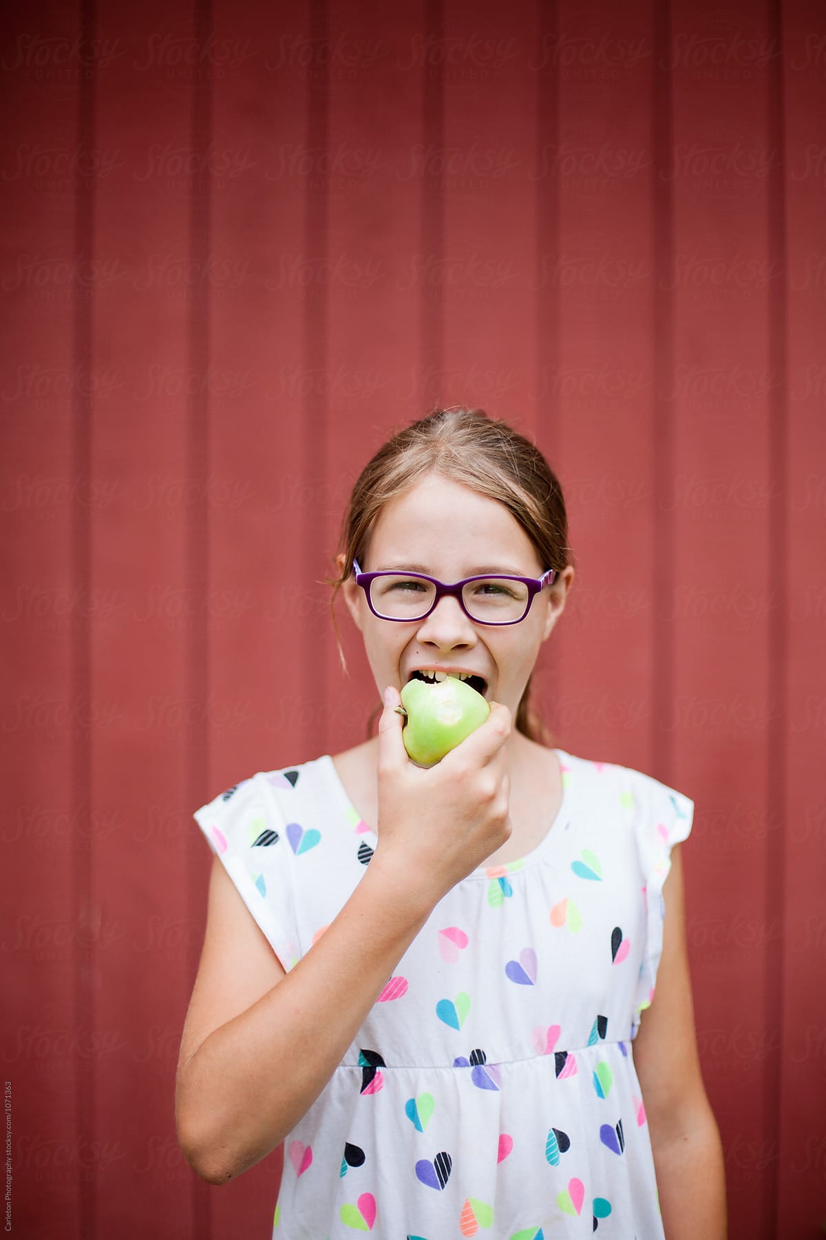 Eleven  year old girl bites into freshly picked green apple