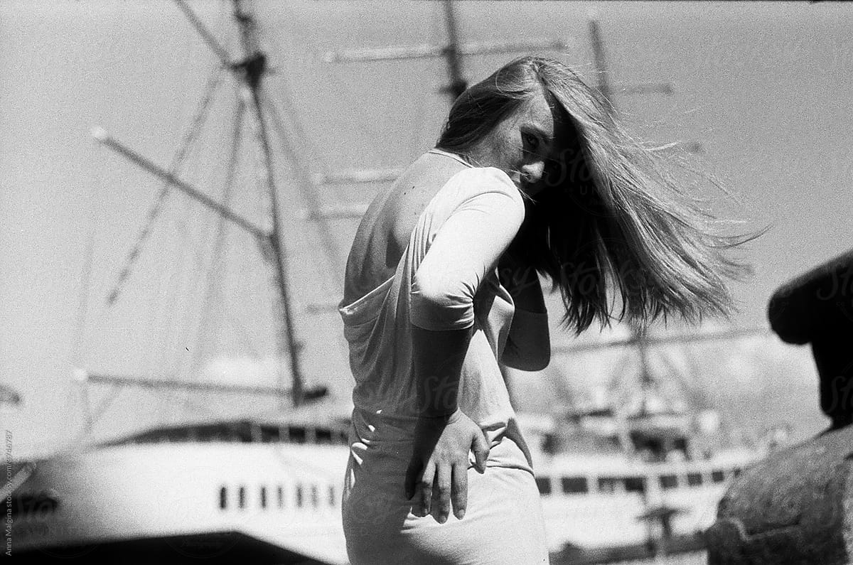 A beautiful blond woman in front of a big sailing yacht