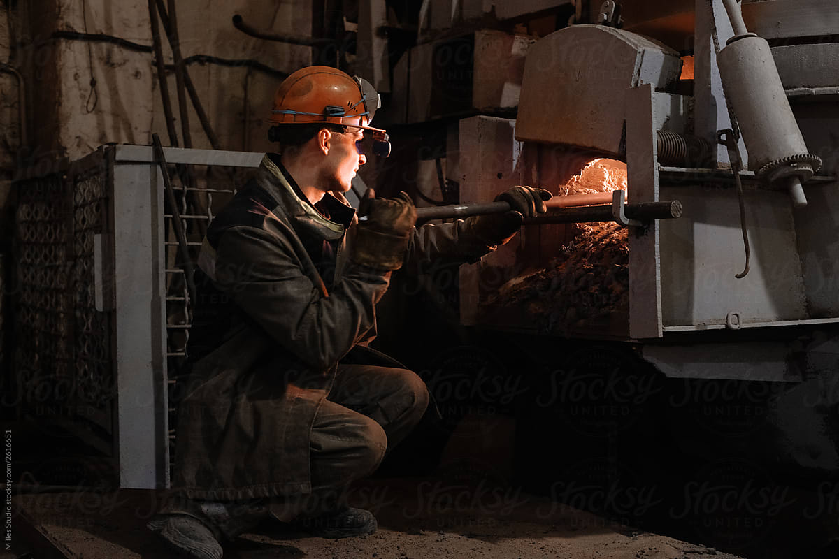 Foundry worker cleaning hot furnace