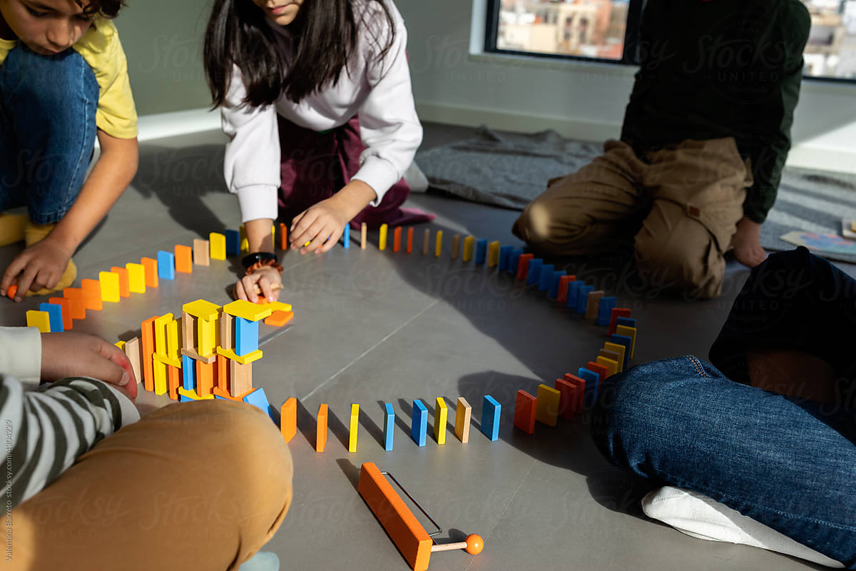 Kids making circuit with dominoes at playroom floor