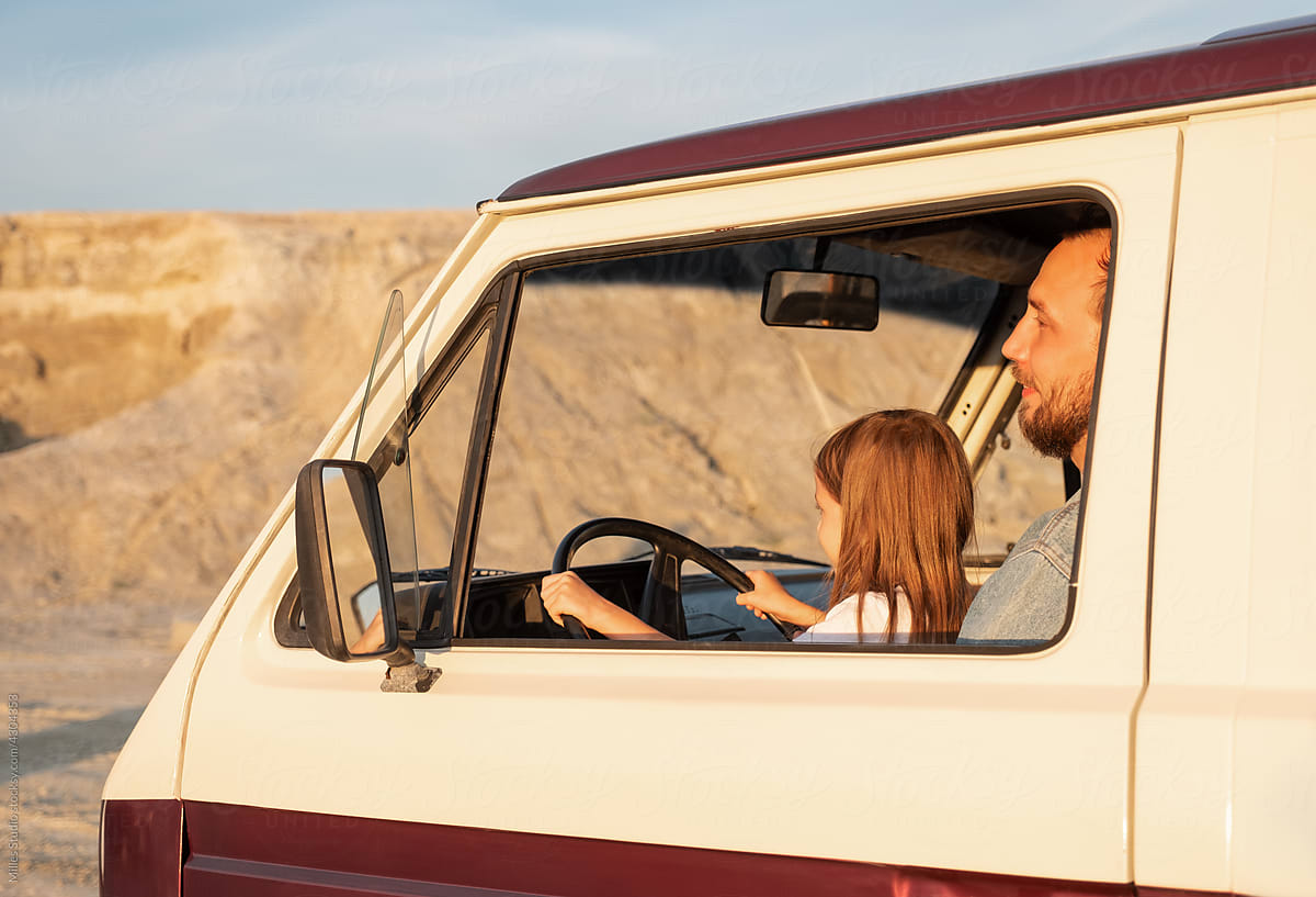 Father and daughter driving van near rock