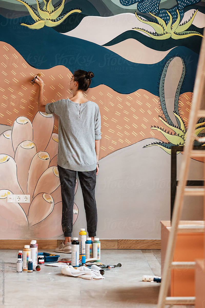 Young woman painting mural on wall