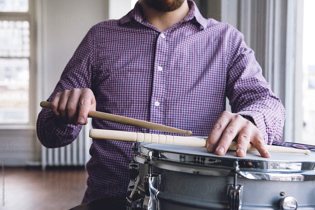 man with snare drum holding onto drum sticks