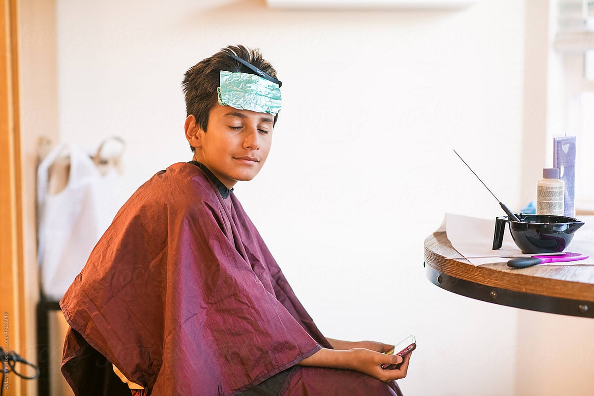 Pre-teen boy dyeing his hair with foil on head