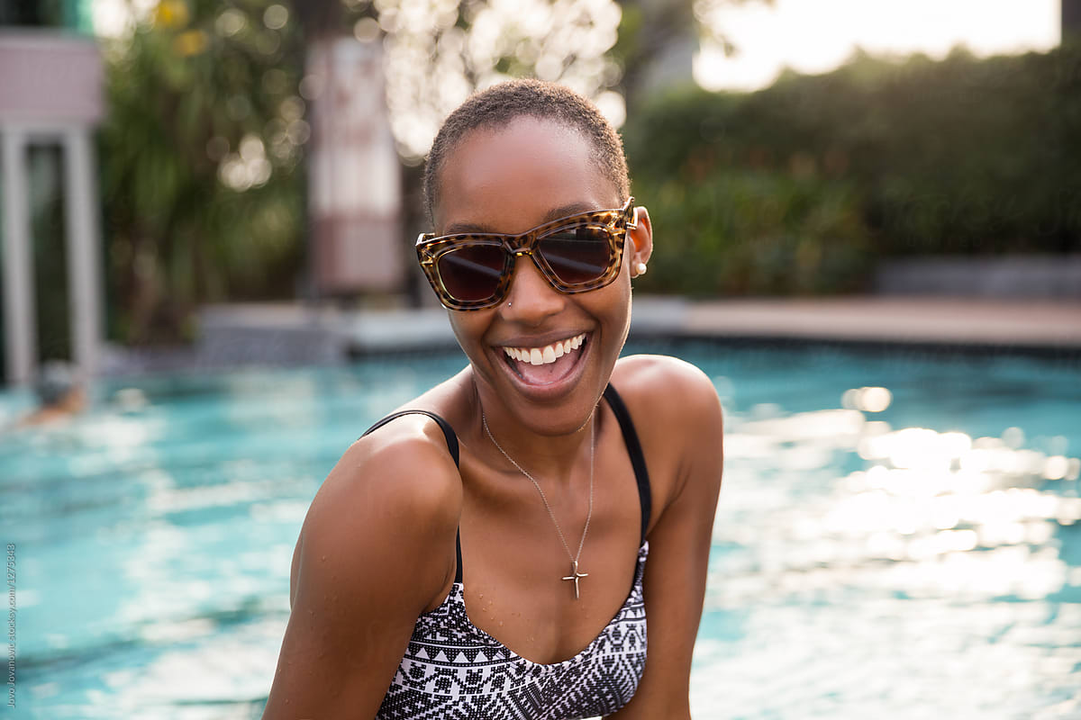 Bald woman smiles next to pool