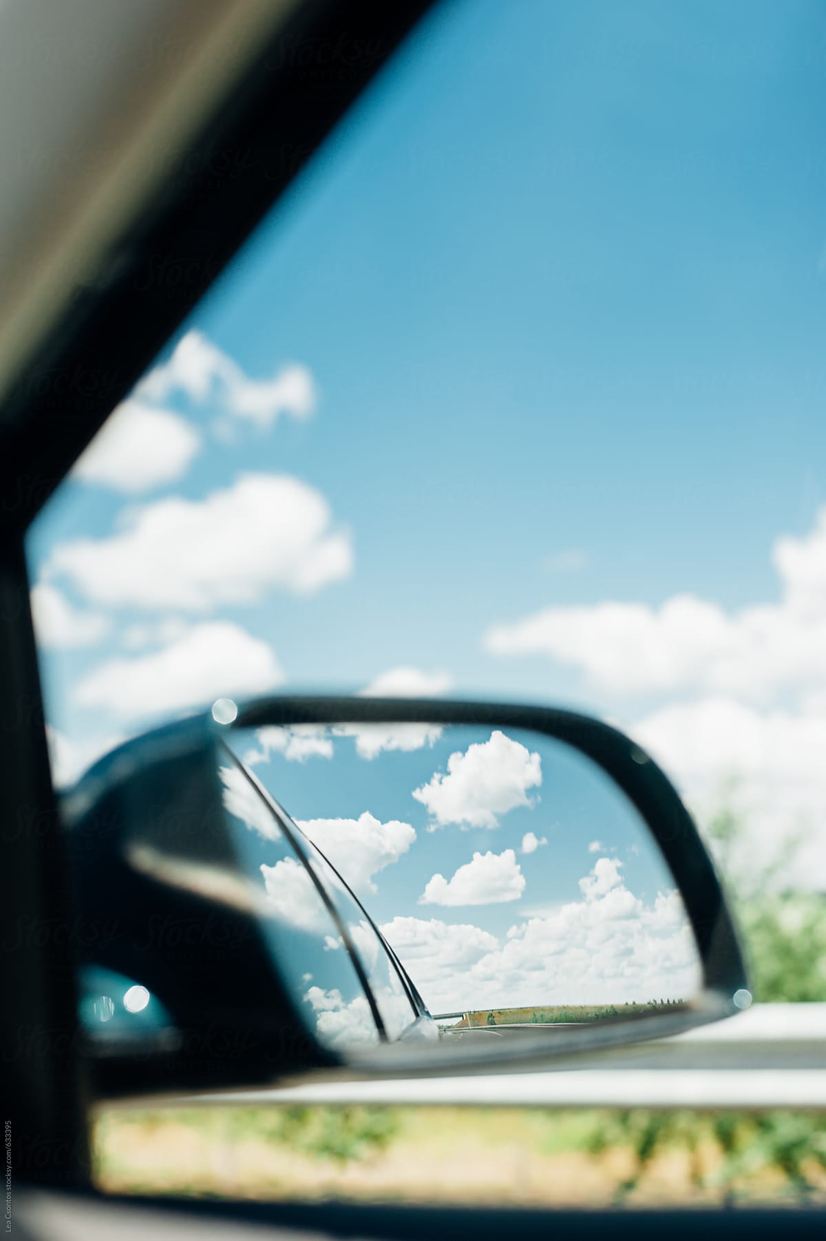View of gorgeous summer clouds in the rearview mirror of a car