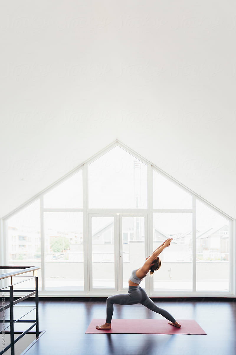 Back view of beautiful young woman doing yoga postures in luxury apartment