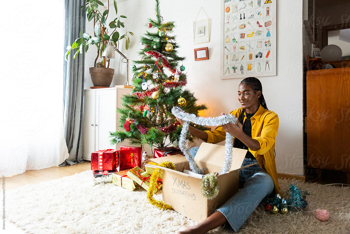 Smiling Woman at home putting out Christmas tinsel