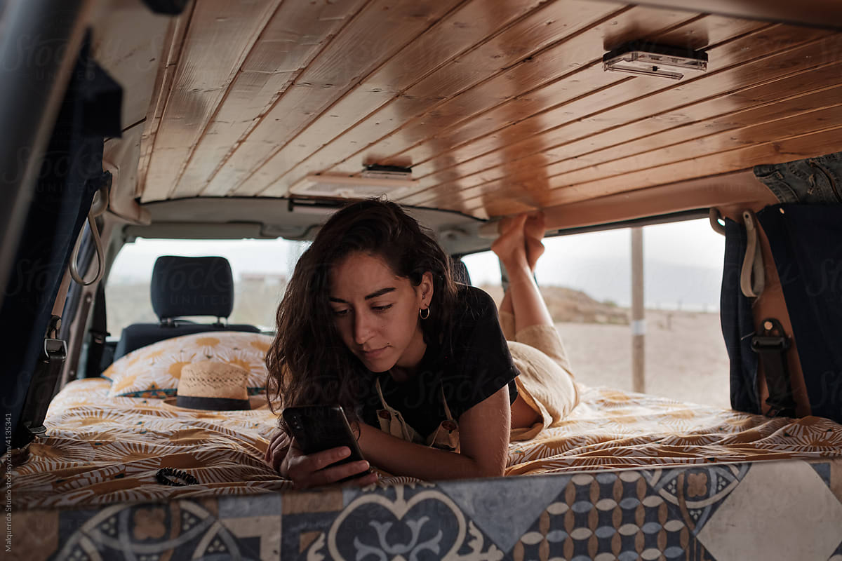 Woman browsing phone inside camper van