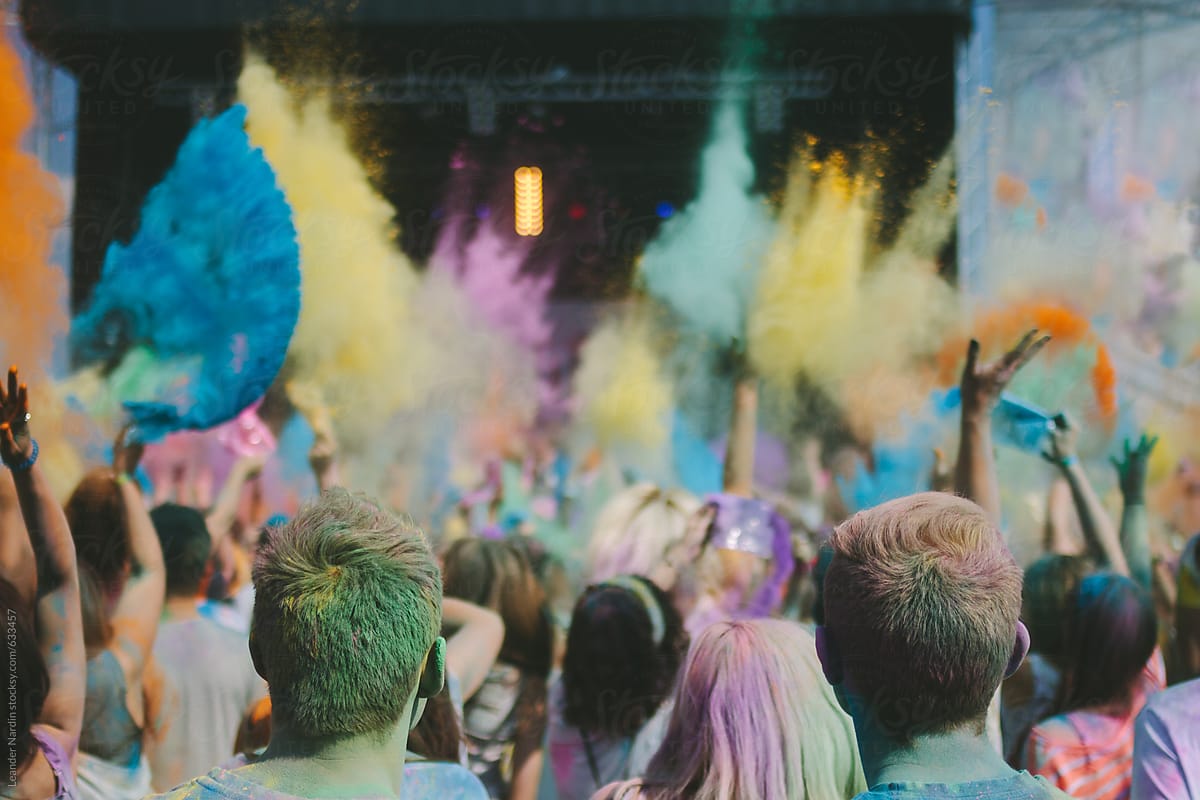 crowd throwing colorful powder in the air at an outdoor music festival